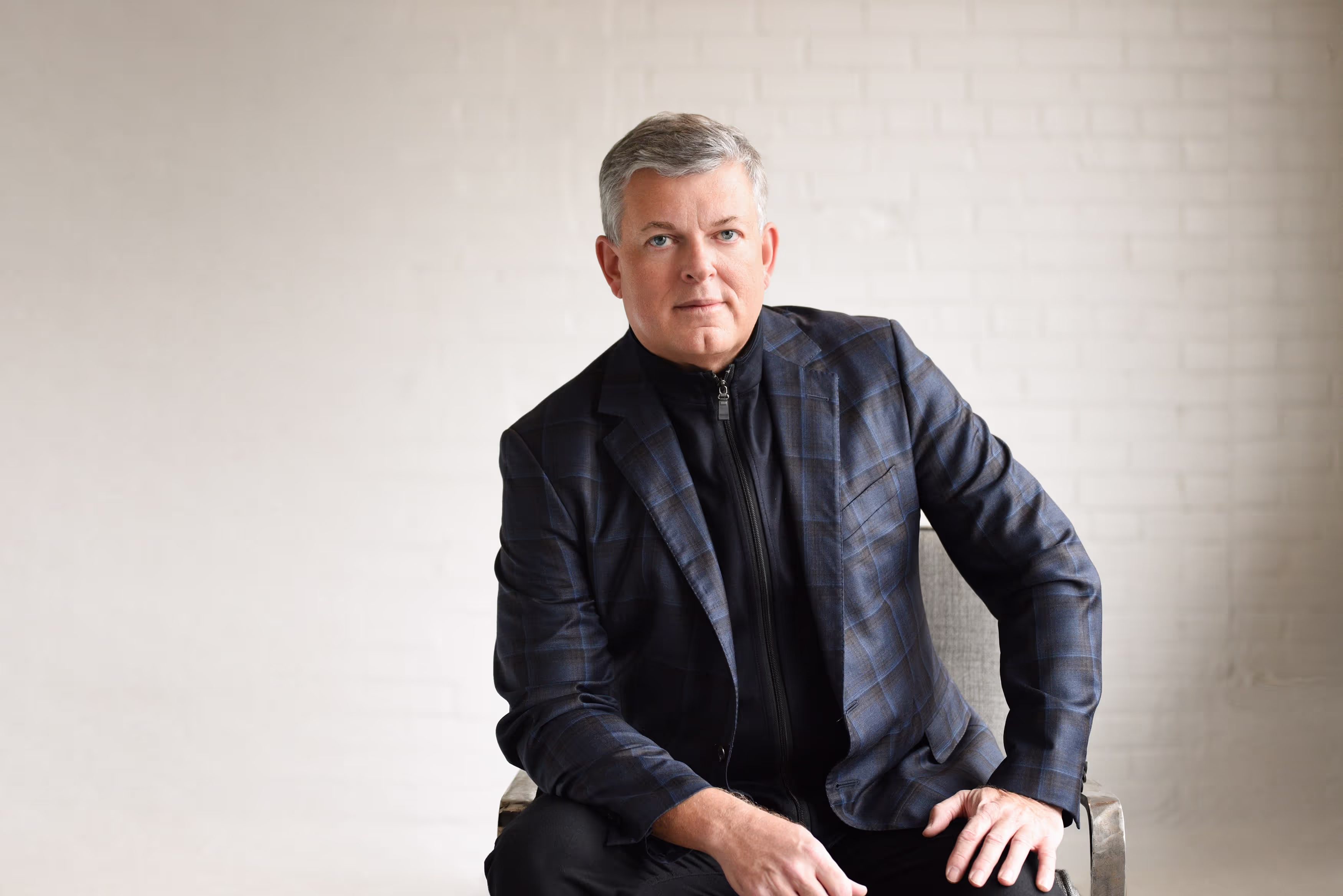 The founder of Targeted Coaching International, sitting confidently with a grey backdrop.