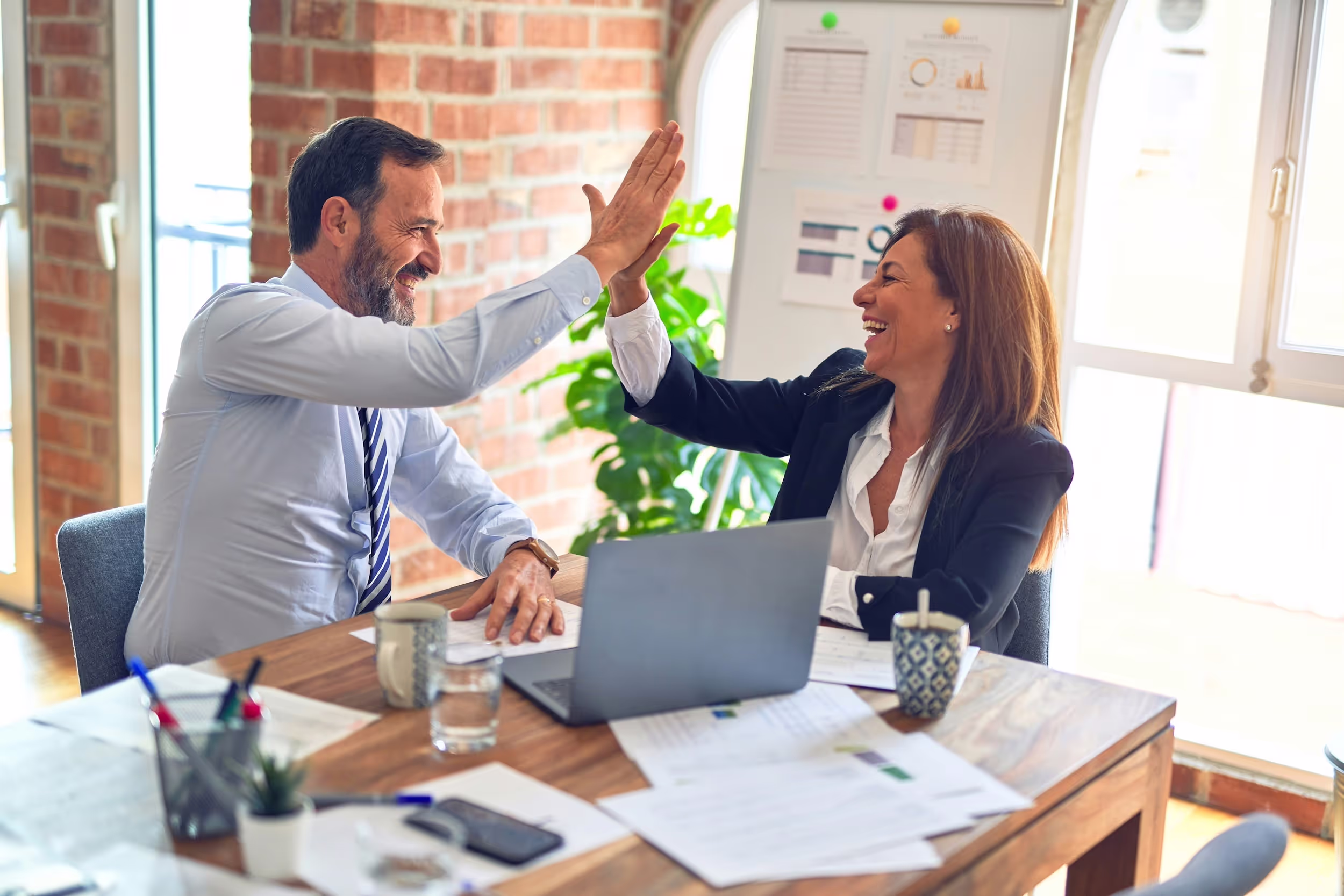 Two professionals sharing a high five over their work. 